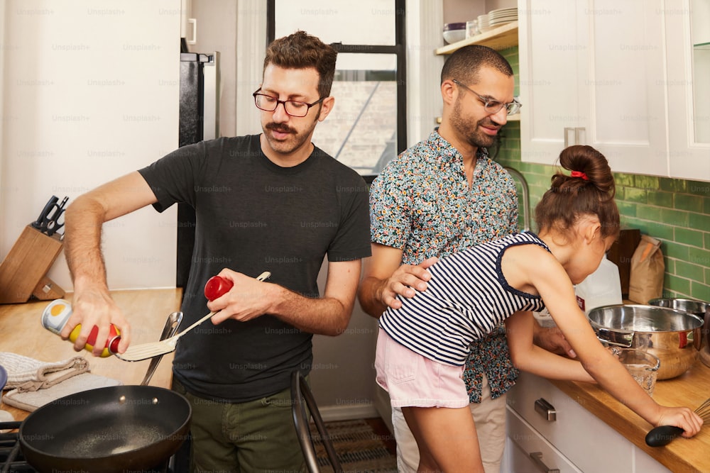 a man and two young girls cooking in a kitchen