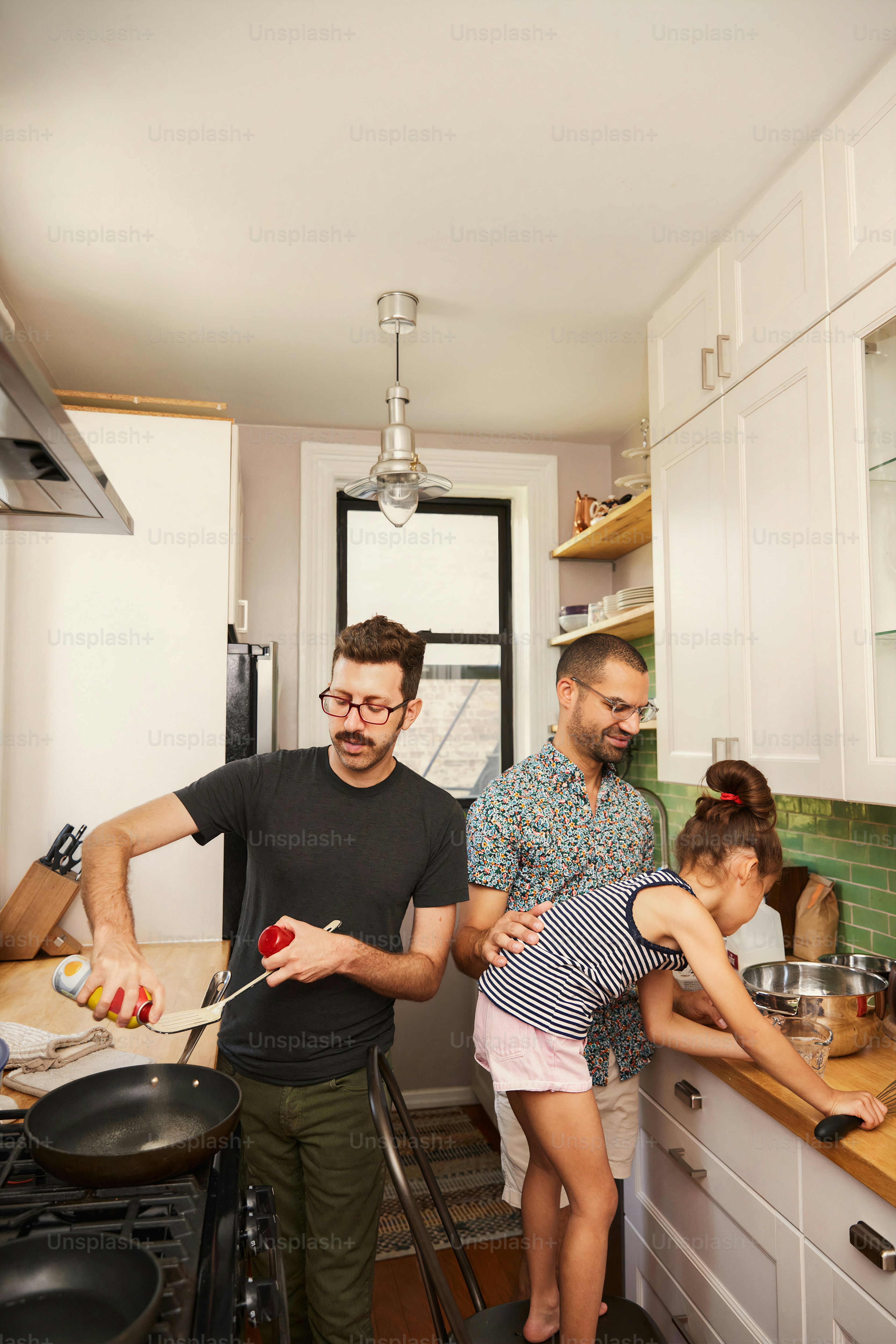 a man standing in a kitchen next to a little girl