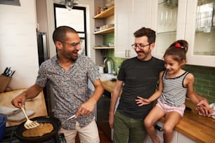 a man and two little girls cooking in a kitchen