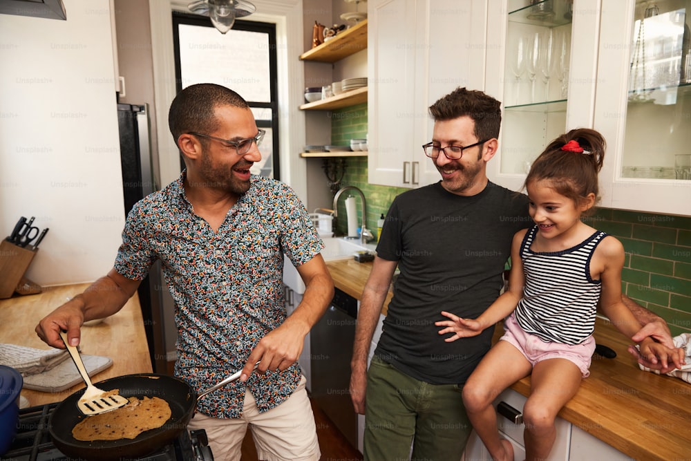 a man and two little girls cooking in a kitchen