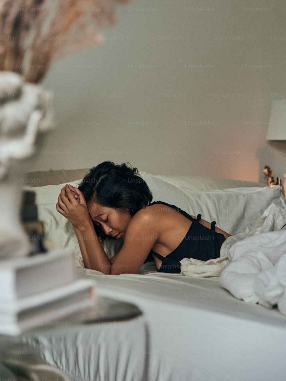 a woman laying in bed with her head on her hands