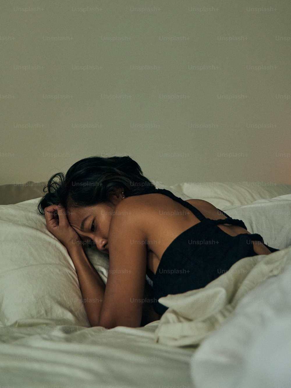 a woman laying in bed with her head on a pillow