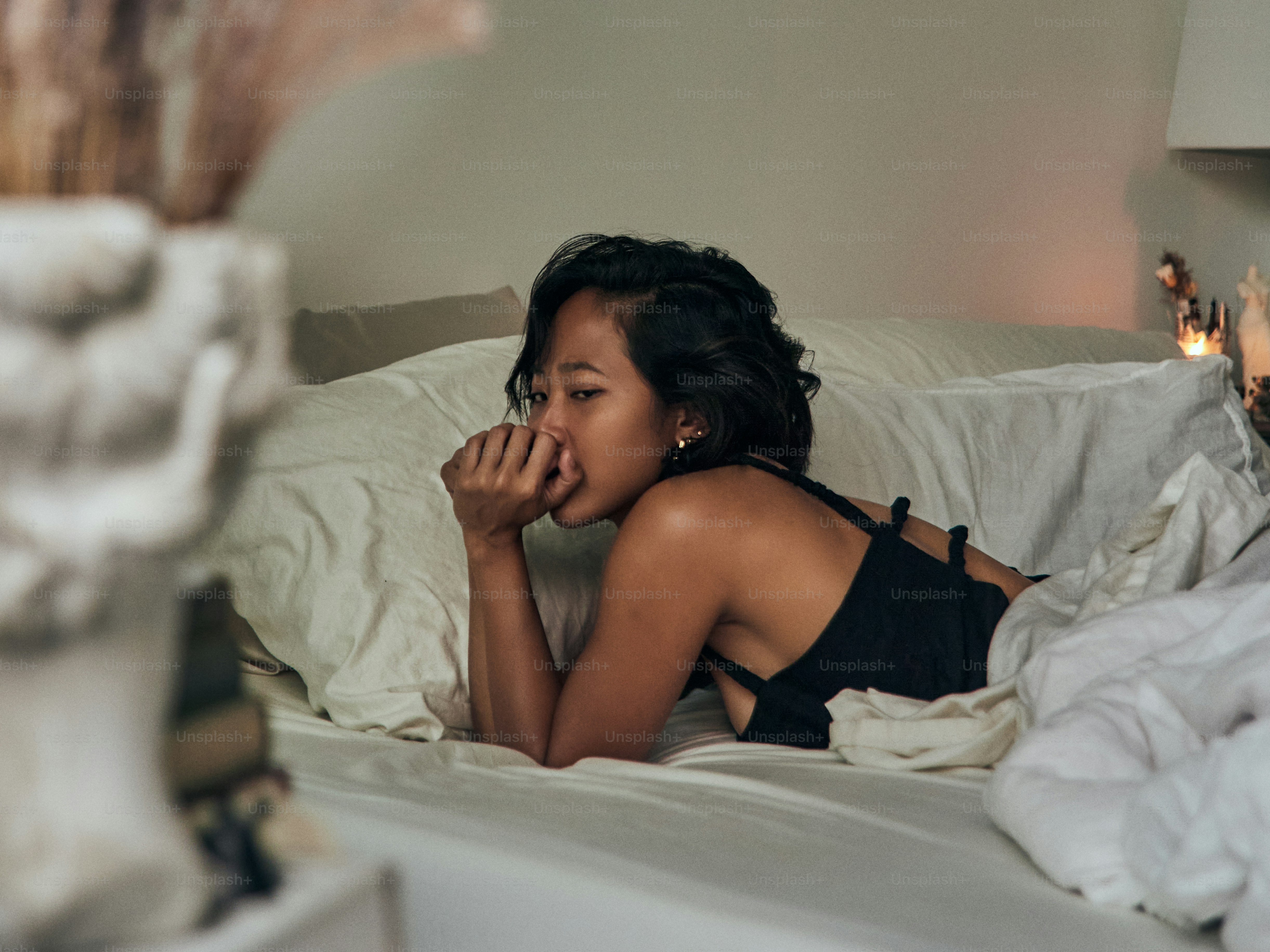 a woman laying in bed with her hand on her face