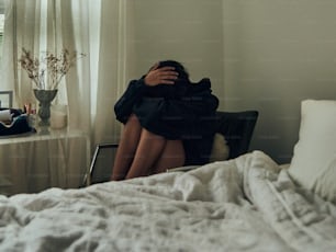 a woman sitting on a bed with her head in her hands
