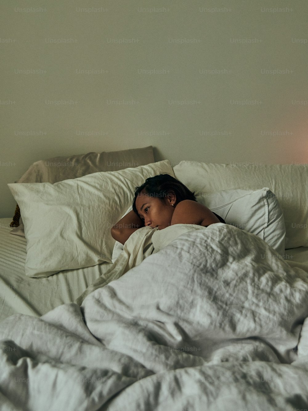 a woman laying in bed with a white comforter