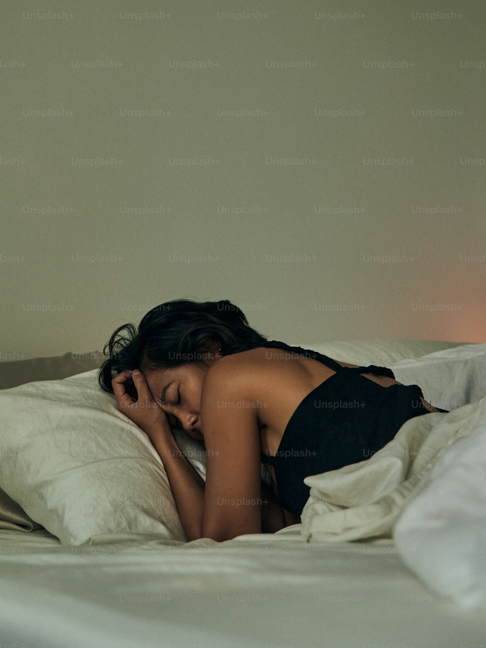 uma mulher deitada na cama com a cabeça em um travesseiro