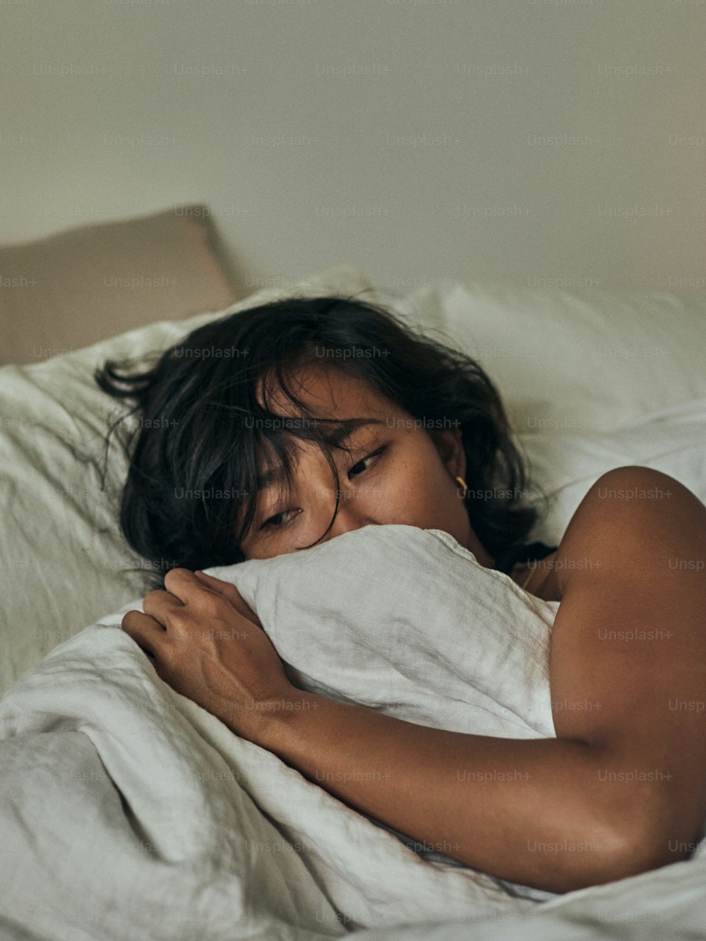 a woman laying in bed with a blanket covering her face