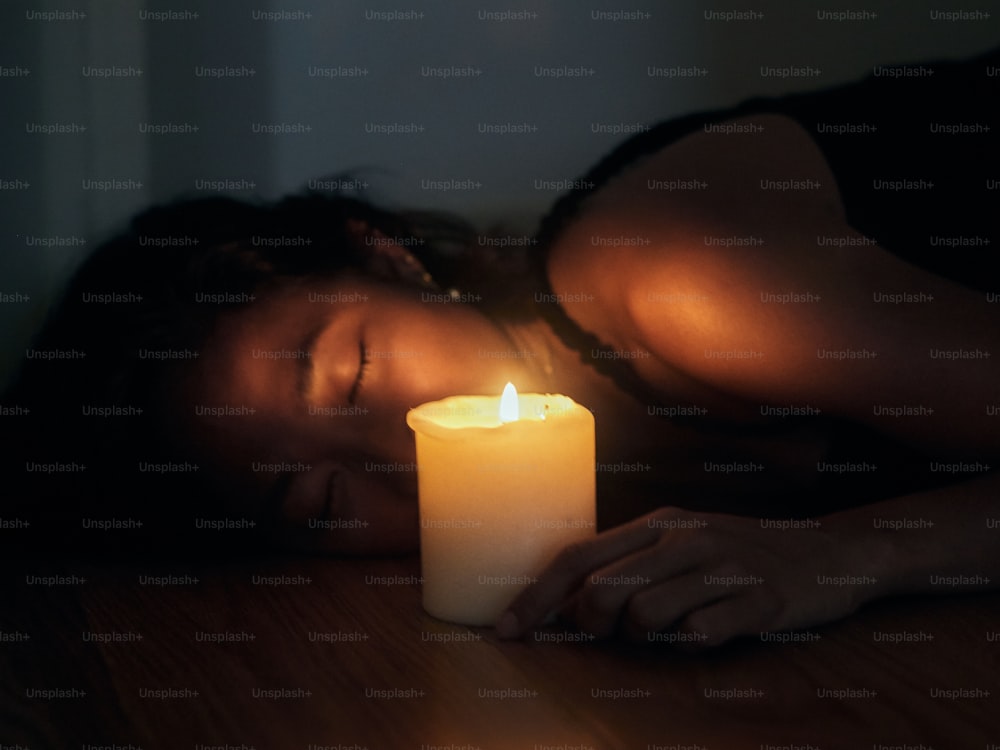 uma mulher deitada no chão ao lado de uma vela acesa