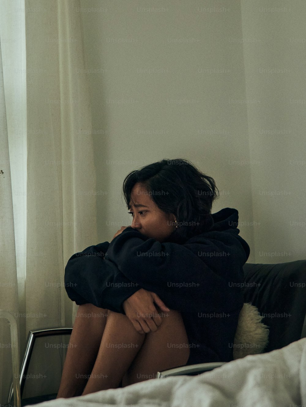 a woman sitting on top of a bed next to a window