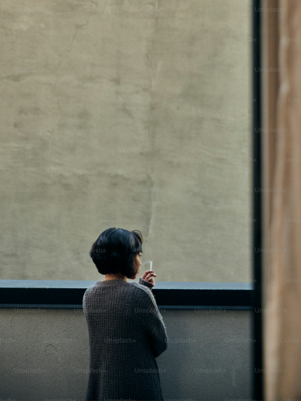 Una mujer mirando por una ventana a algo afuera