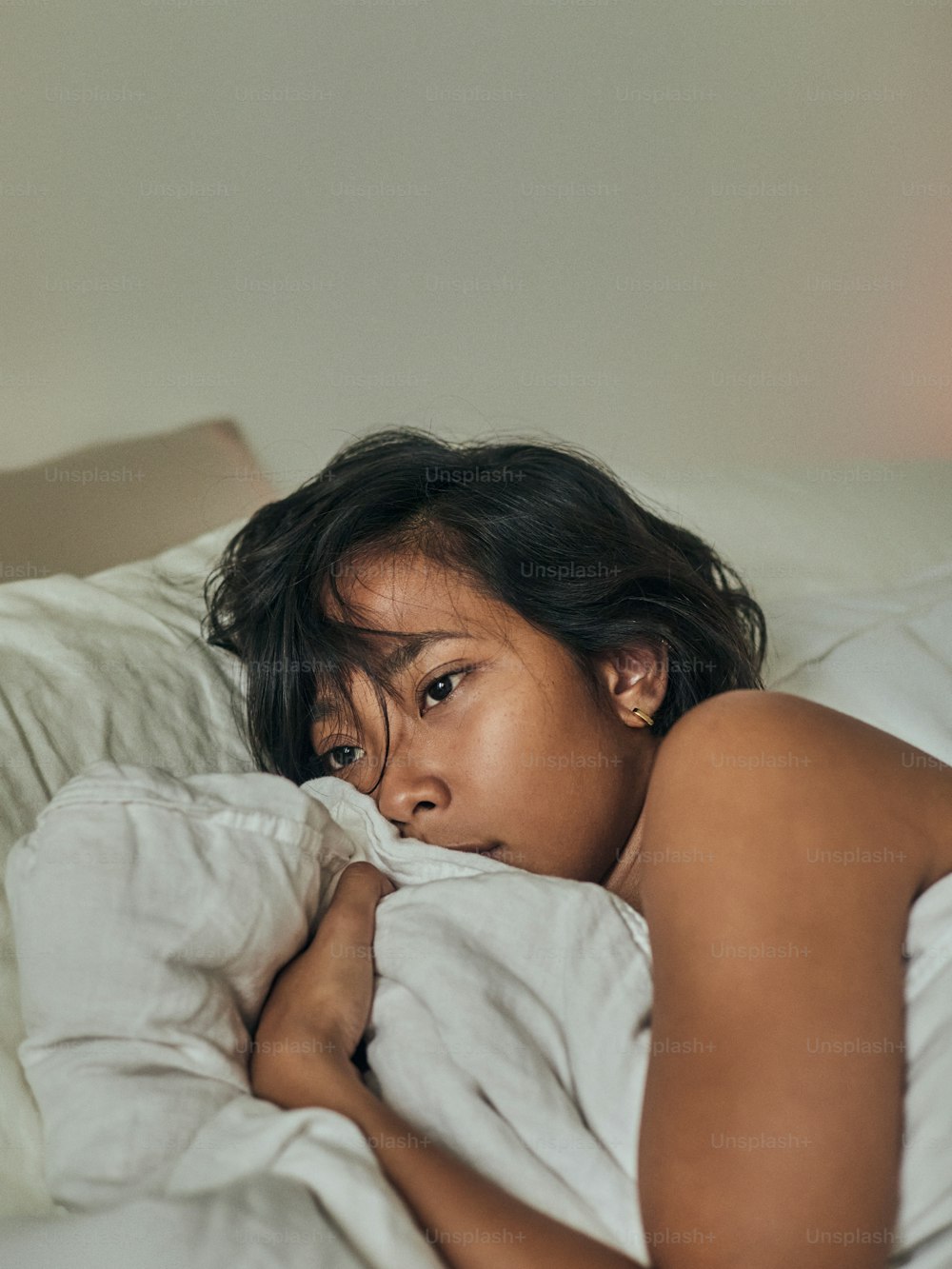 a woman laying in bed with a white comforter