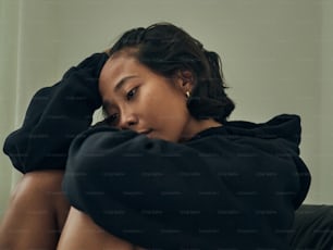 a woman sitting on a couch with her hands on her head