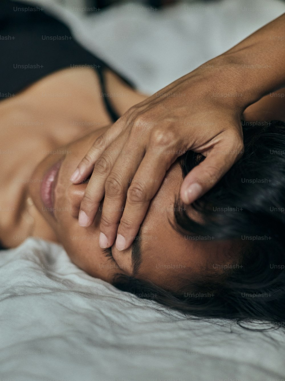 a woman laying on a bed with her hands on her head