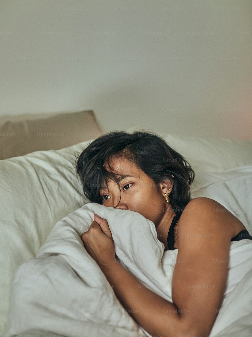 a woman laying in bed with a white blanket