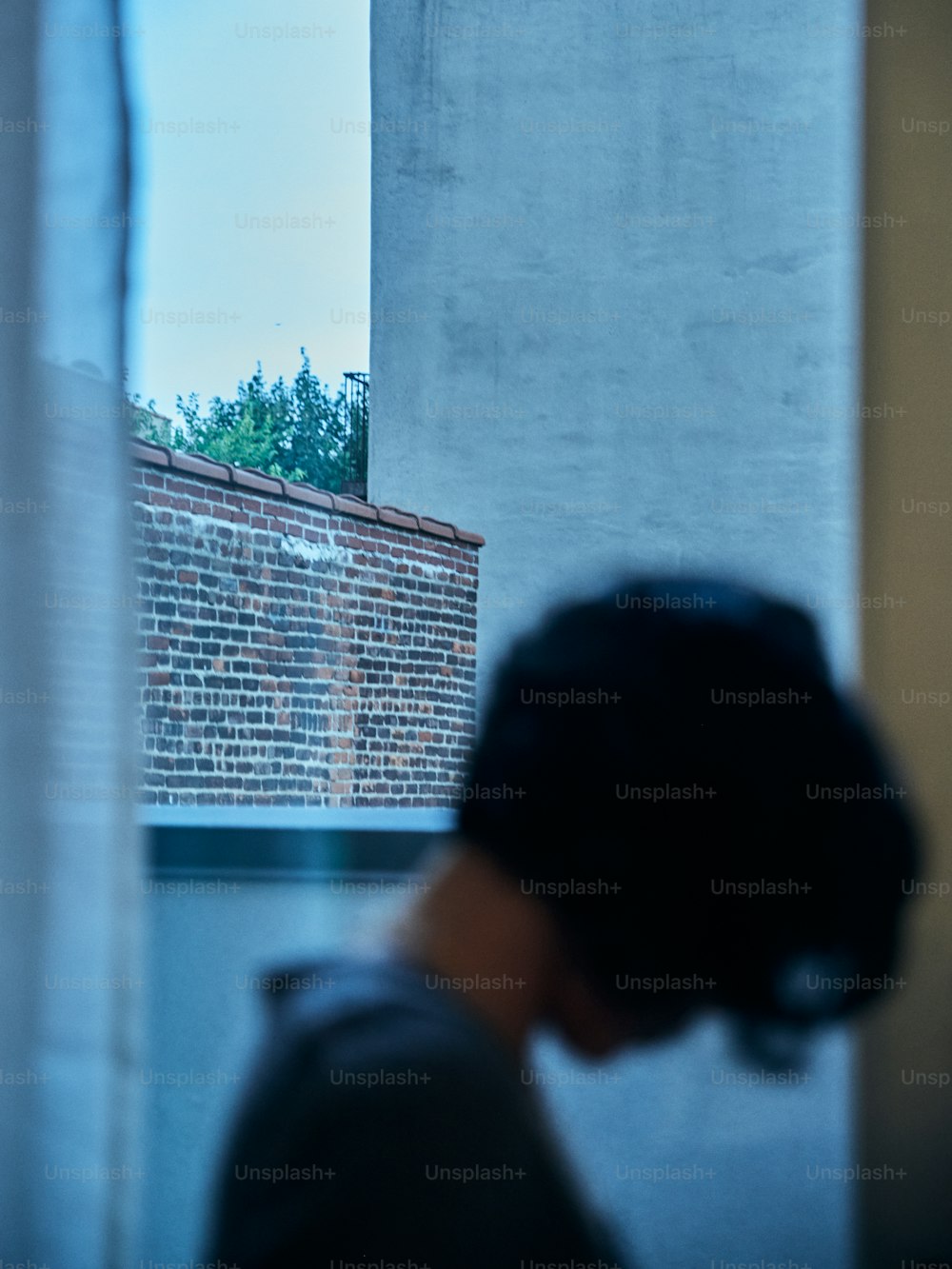 a person looking out a window at a brick building