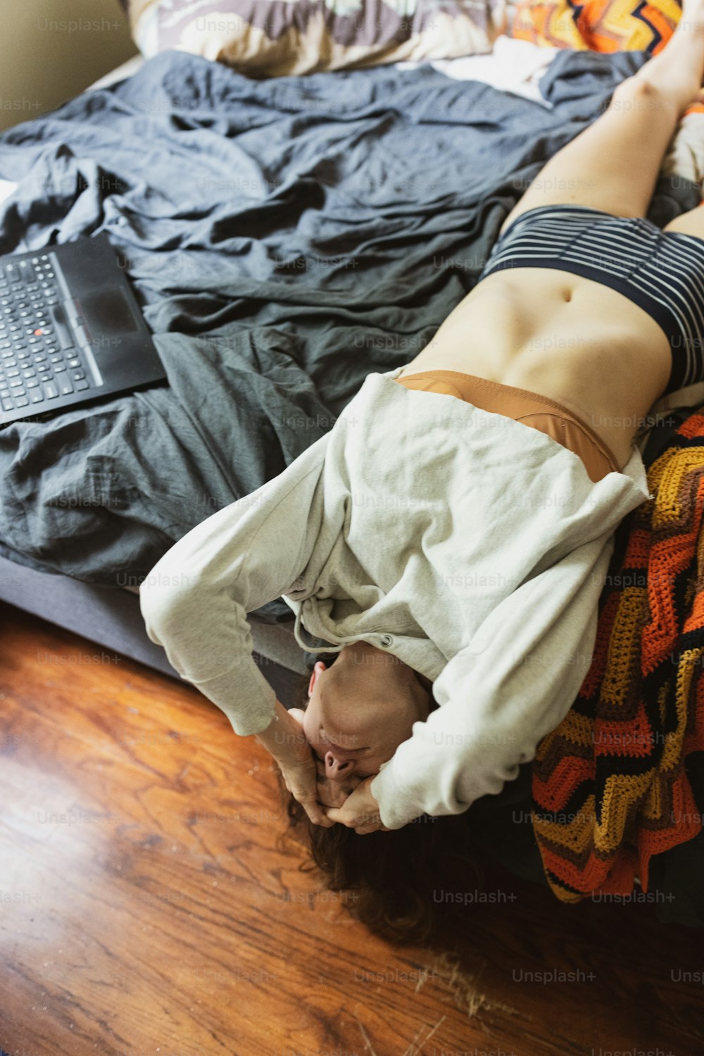 a woman laying on top of a bed next to a laptop computer