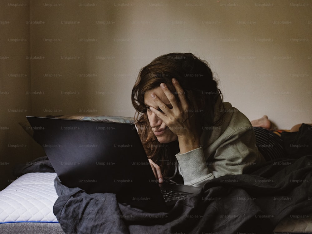 노트북 컴퓨터를 사용하여 침대에 누워 있는 여자