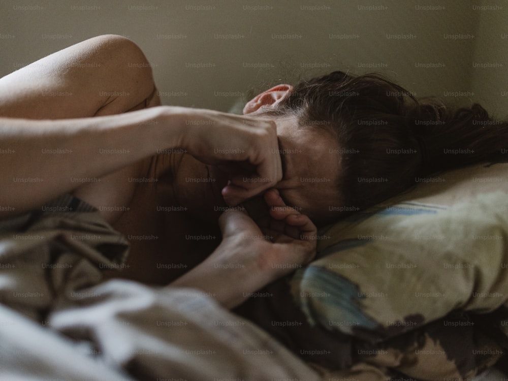 a woman laying in bed with her hand on her face