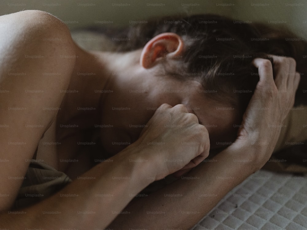una donna sdraiata su un letto con la testa sulle mani