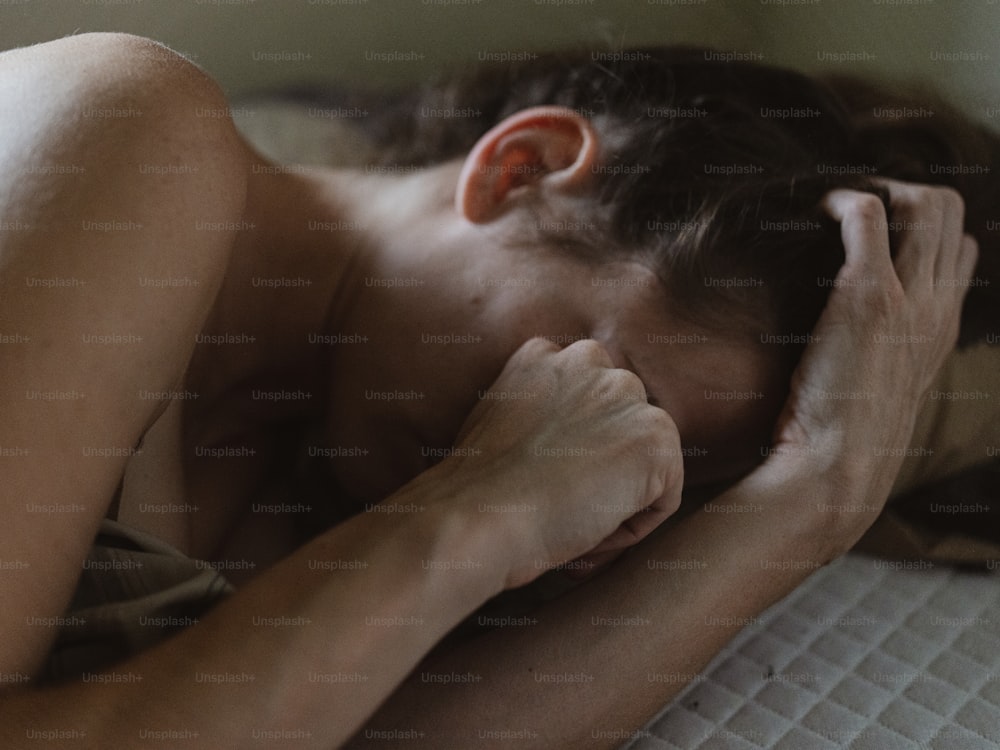 a woman laying on a bed with her head on her hands