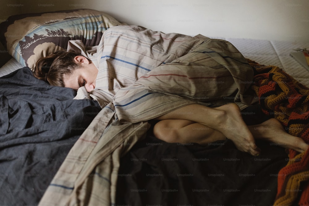 a person laying in a bed with a blanket