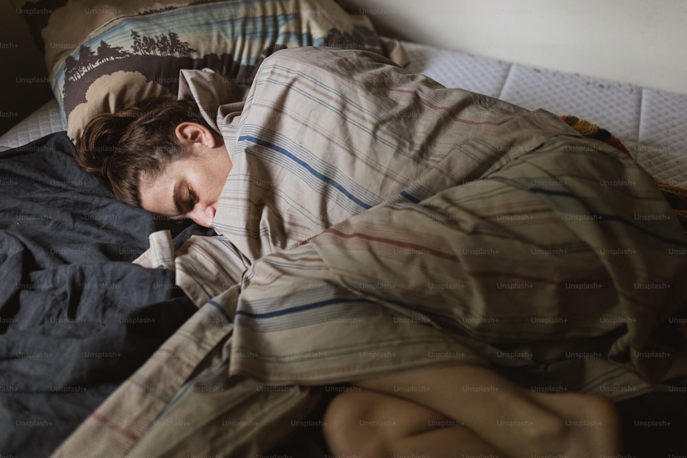 uma pessoa dormindo em uma cama com um cobertor