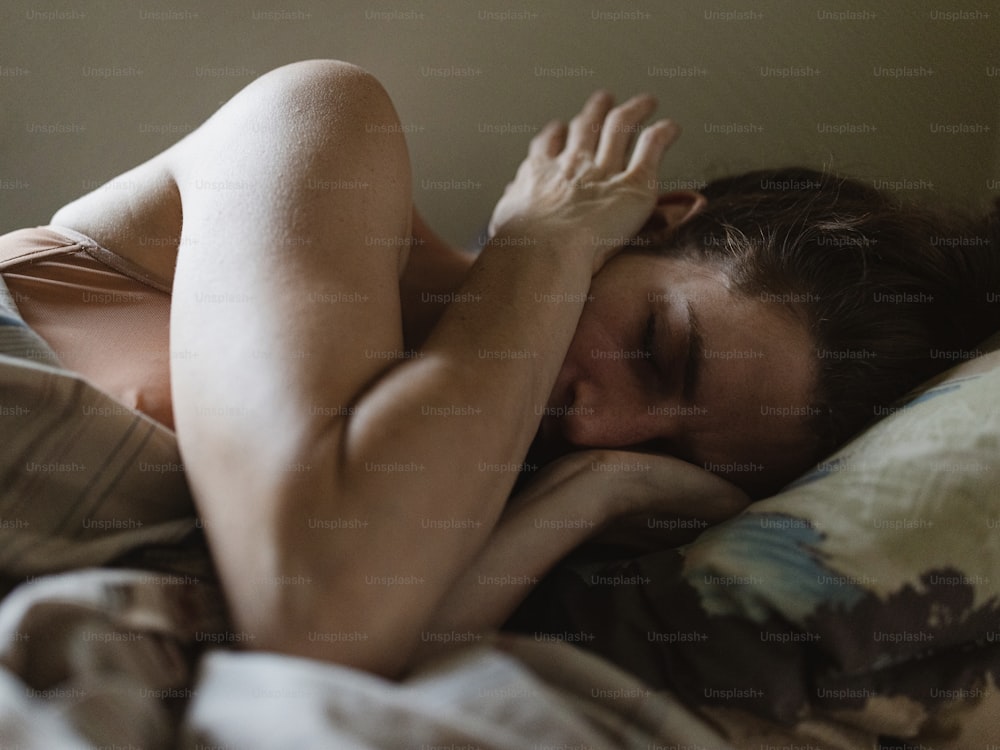 a naked woman laying in bed with her head on the pillow