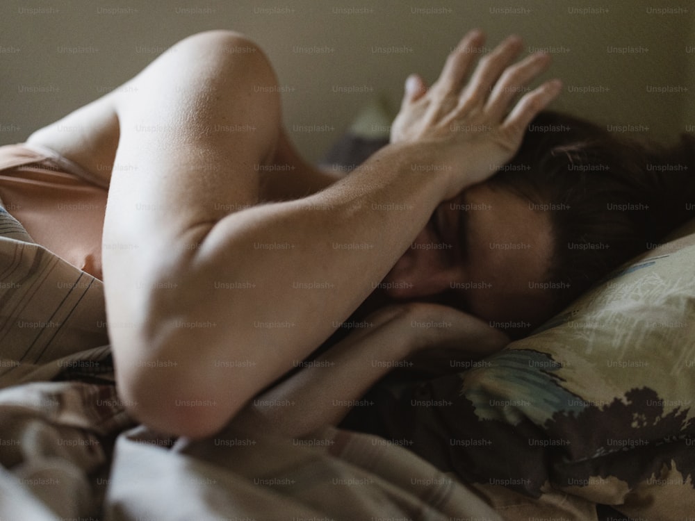 une femme allongée dans son lit, la tête sur les mains
