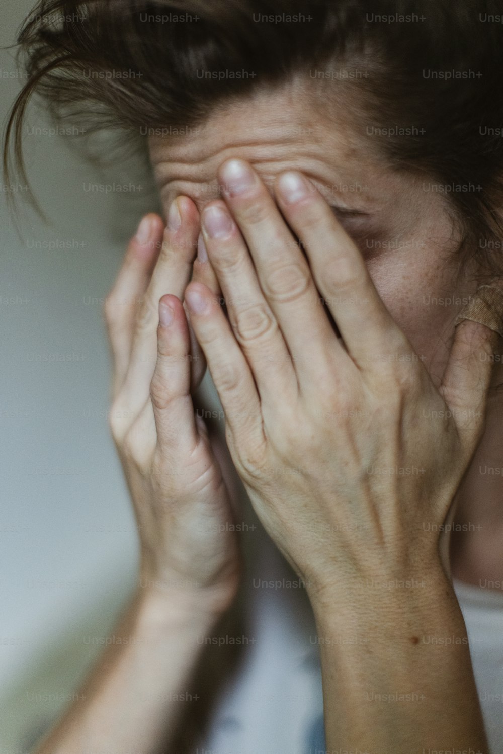 una donna che si copre il viso con le mani