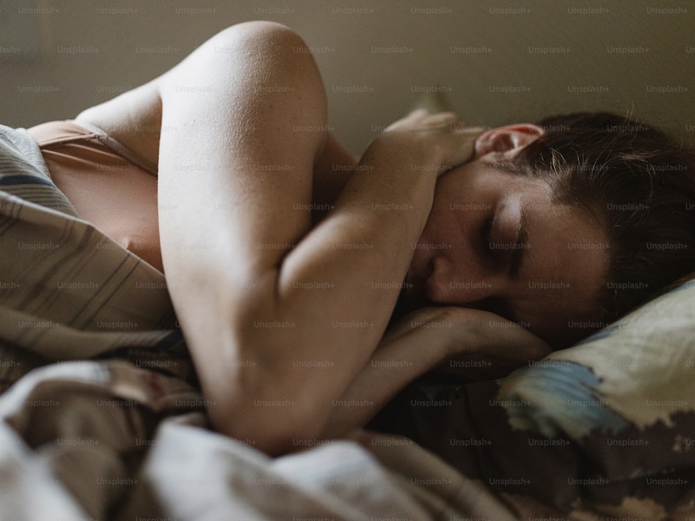 Una mujer acostada en la cama con la cabeza sobre la almohada
