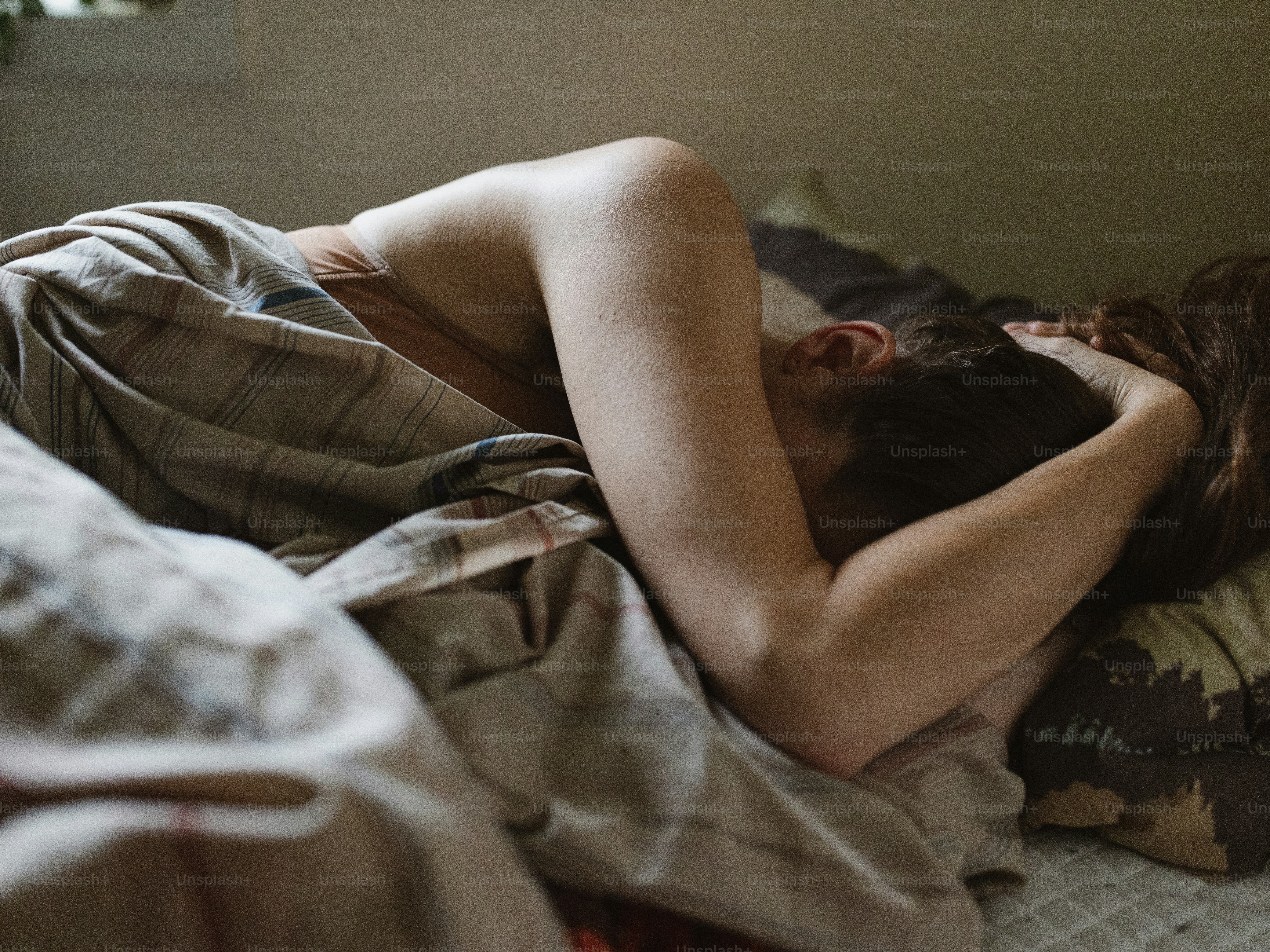 a woman laying in bed with her head on a pillow