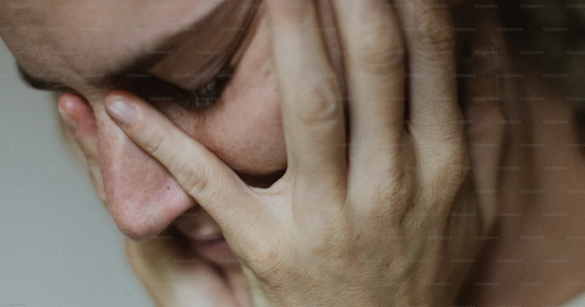 A woman holding her hand to her face photo – Head in hands Image on ...