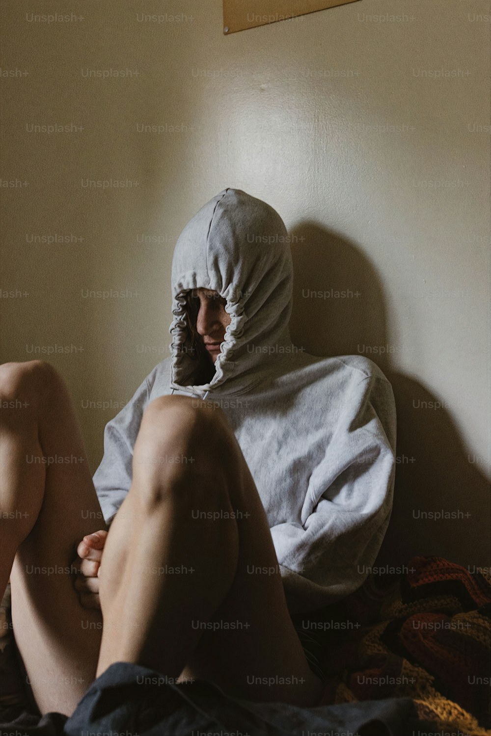 a man in a white hoodie sitting on a bed
