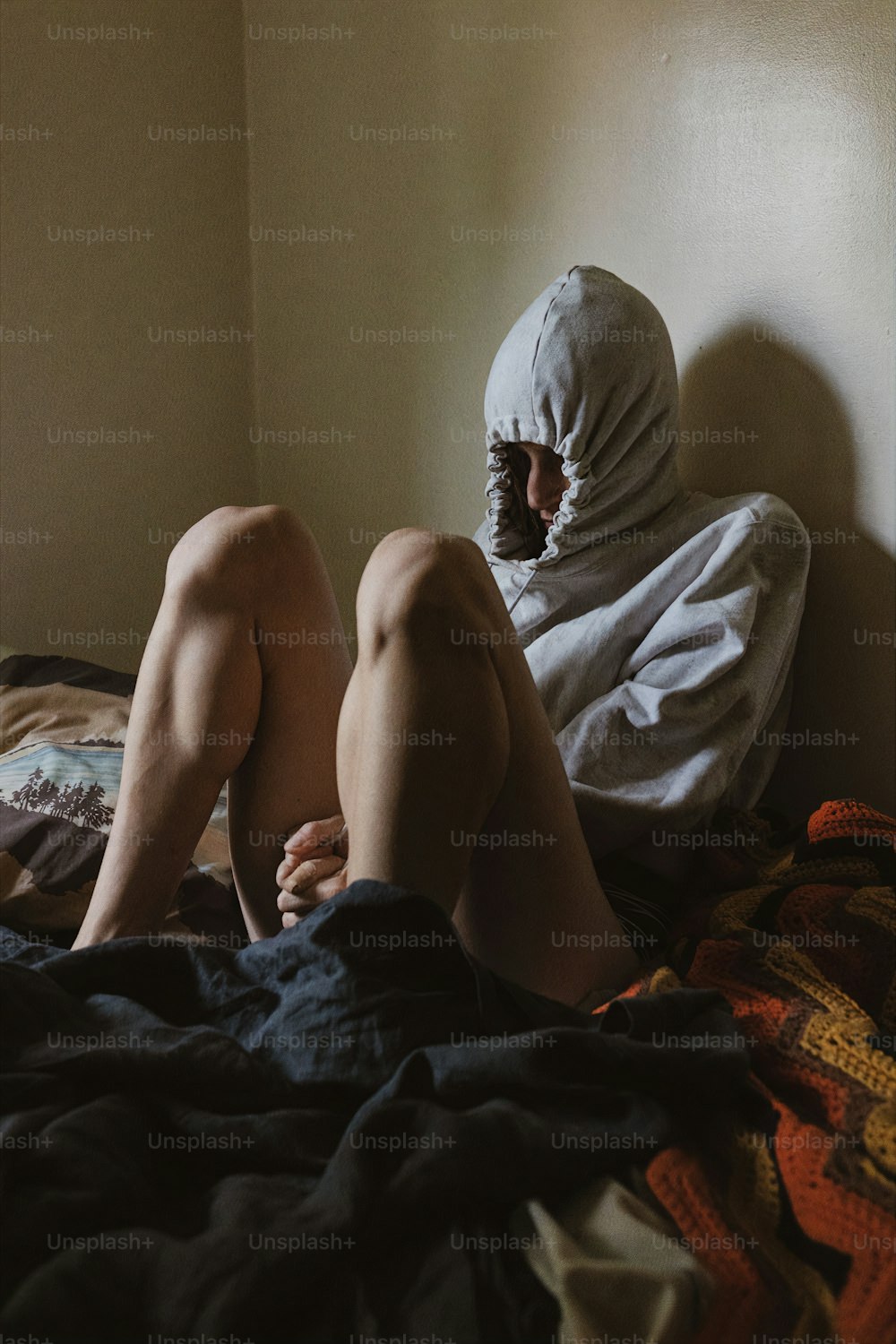eine Person mit weißer Kopfbedeckung, die auf einem Bett sitzt