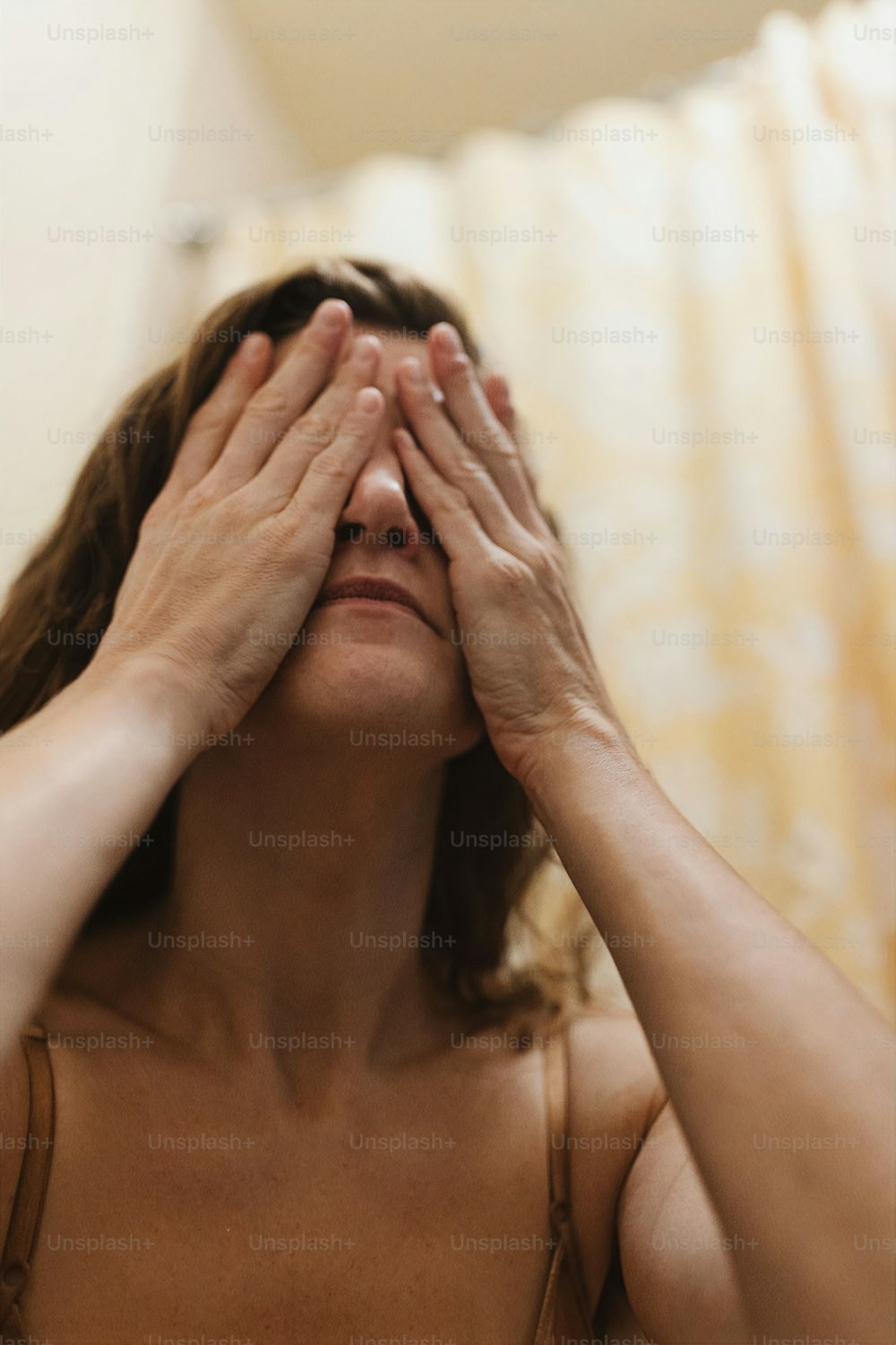 uma mulher cobrindo os olhos com as mãos