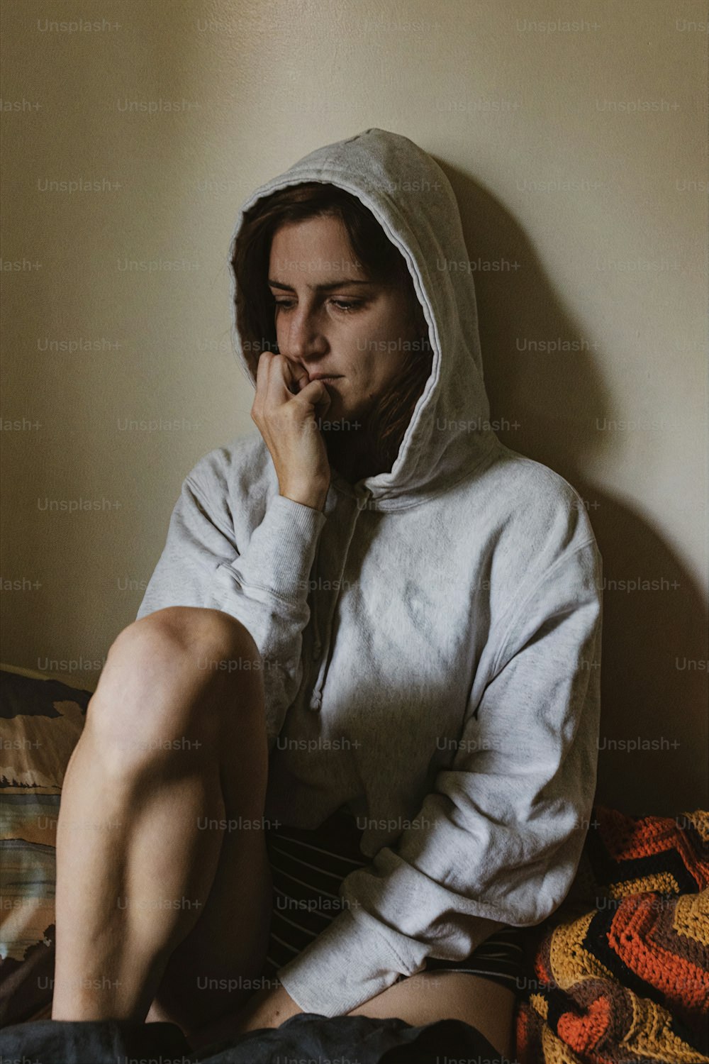 a person sitting on a bed with a hoodie on
