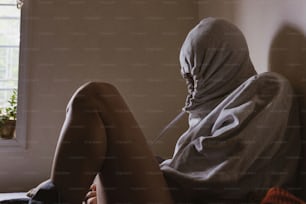 a person sitting on a bed with a head covering