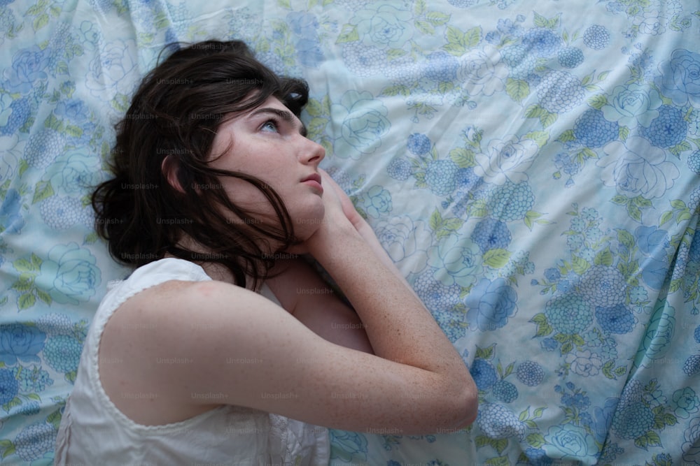 a woman laying on top of a bed under a blanket