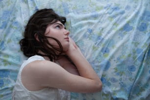 a woman laying on top of a bed under a blanket