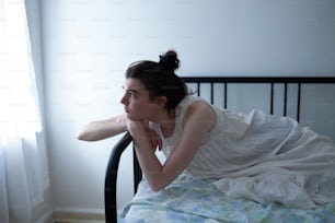 a woman in a white dress laying on a bed
