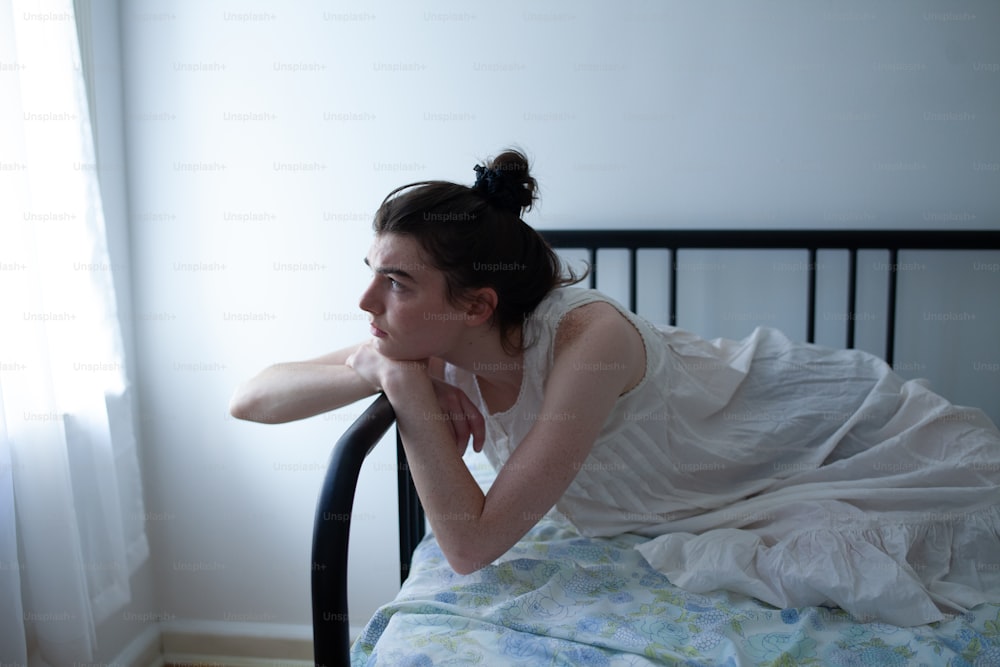a woman in a white dress laying on a bed