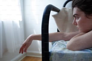 a woman laying in a bed with her arm resting on a pillow