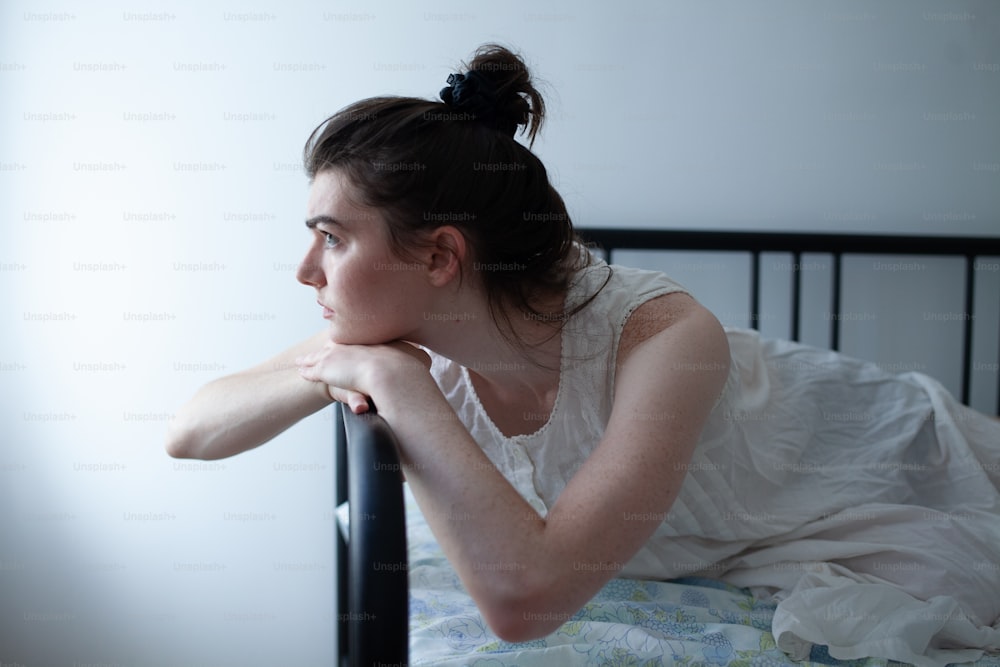 a woman in a white dress laying on a bed