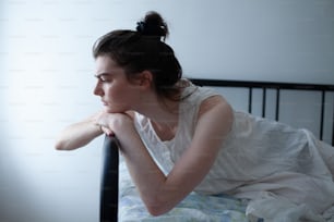 Une femme en robe blanche allongée sur un lit
