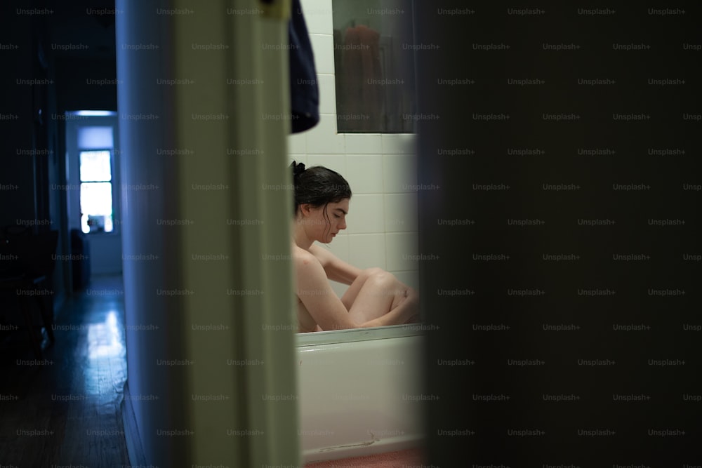 a woman sitting in a bathtub in a bathroom