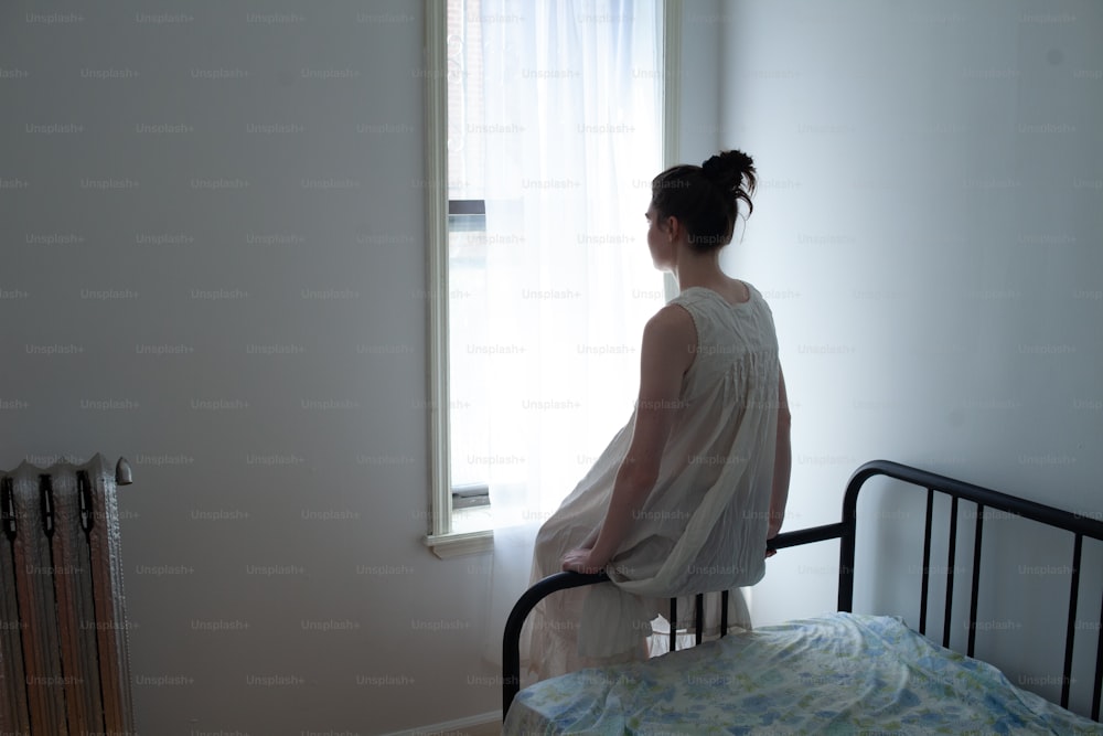 a woman standing on a bed looking out a window