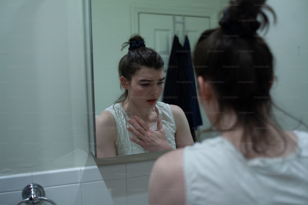 Una mujer mirándose a la cara en el espejo