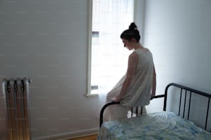 a woman in a white dress standing on a bed