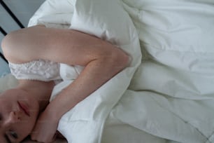 a woman laying in a bed with a white comforter