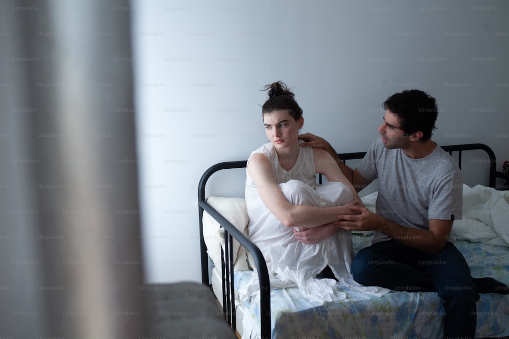 Un hombre sentado junto a una mujer en una cama